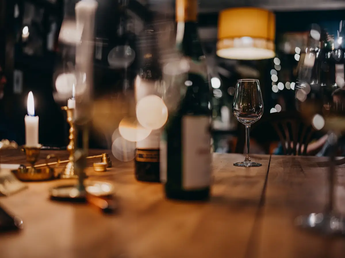 A candlelit restaurant table with a wine glass and bottle, representative of the evening's dinner service