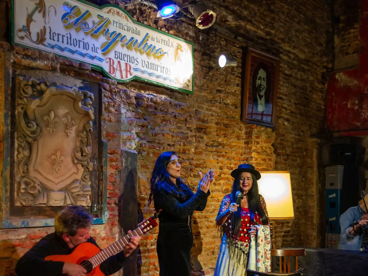Two singers and a guitarist performing at a Buenos Aires tango bar